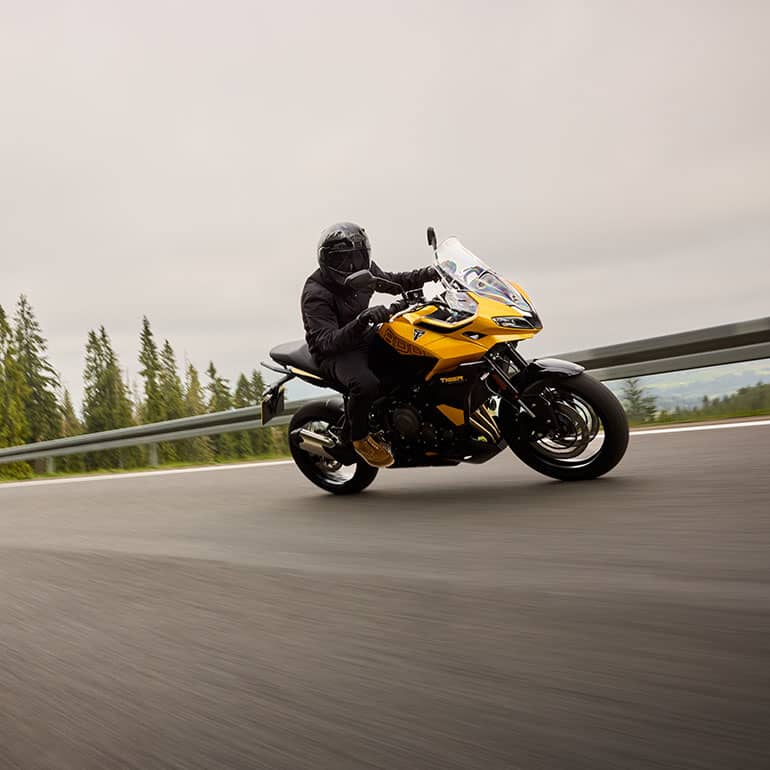 Back left view of Tiger Sport 800 Tour on a road with a field in the background
