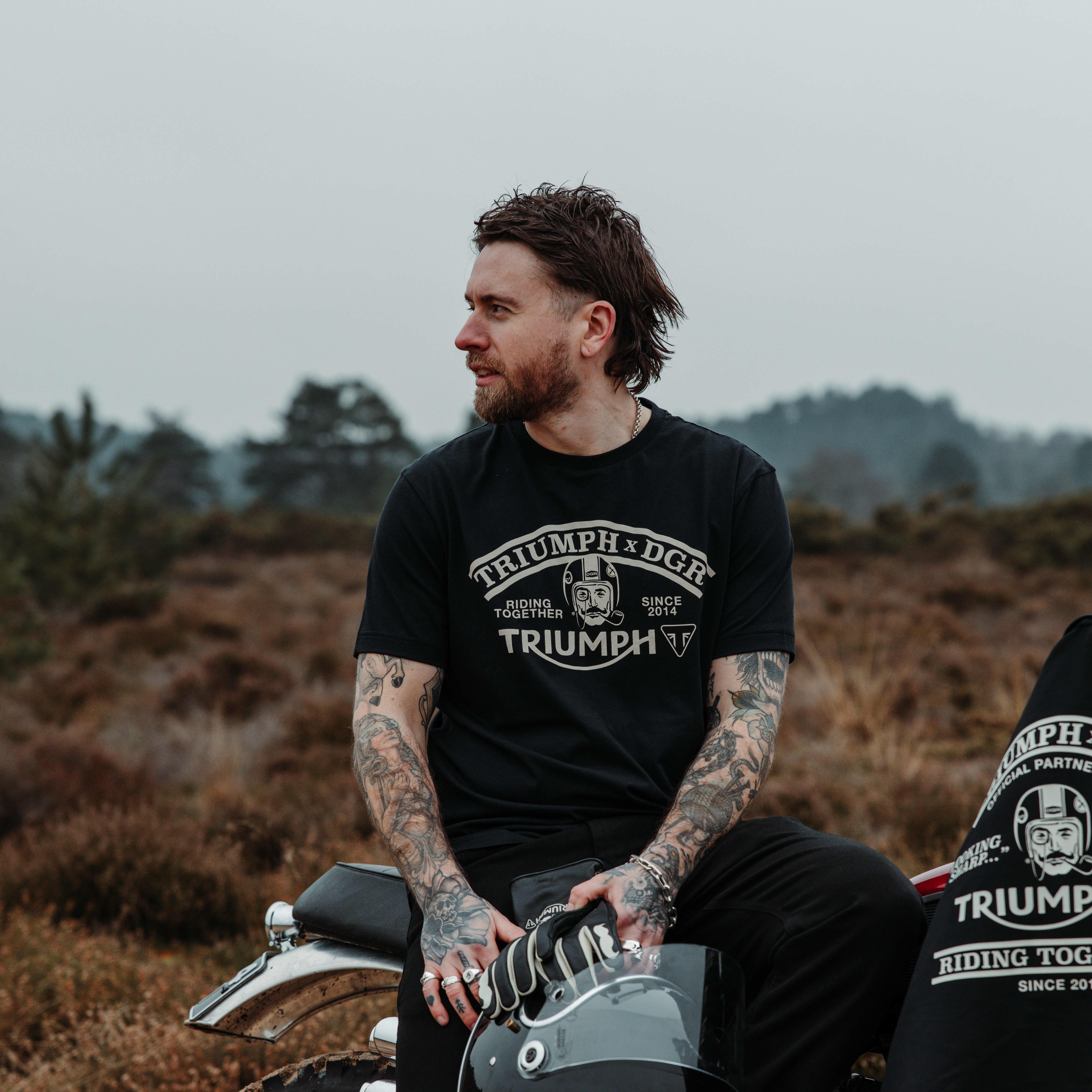 Man sitting on bike wearing a Triumph x DGR t-shirt