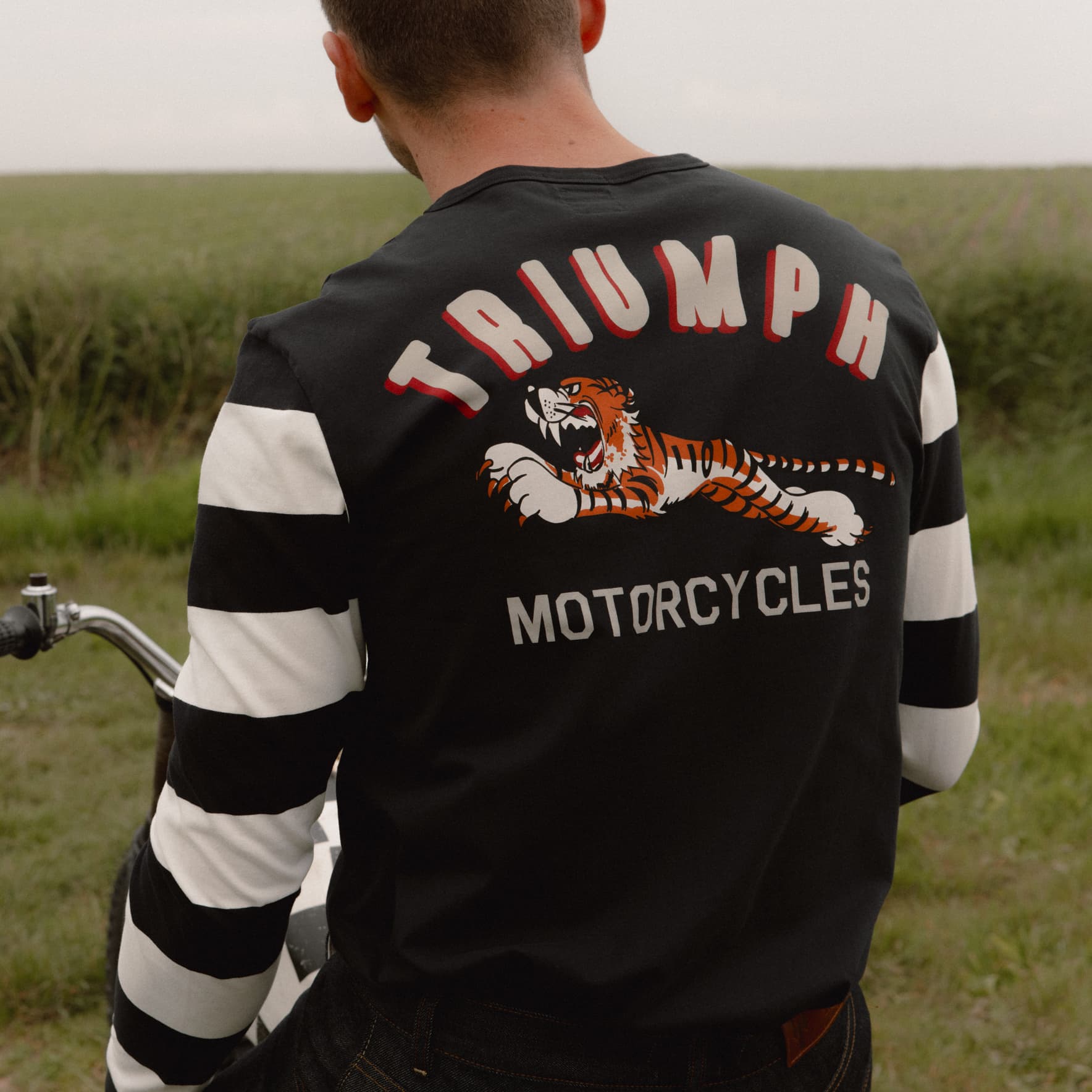 Man in a field wearing Triumph Motorcycles Heritage Super Track Long Sleeve Striped T-shirt
