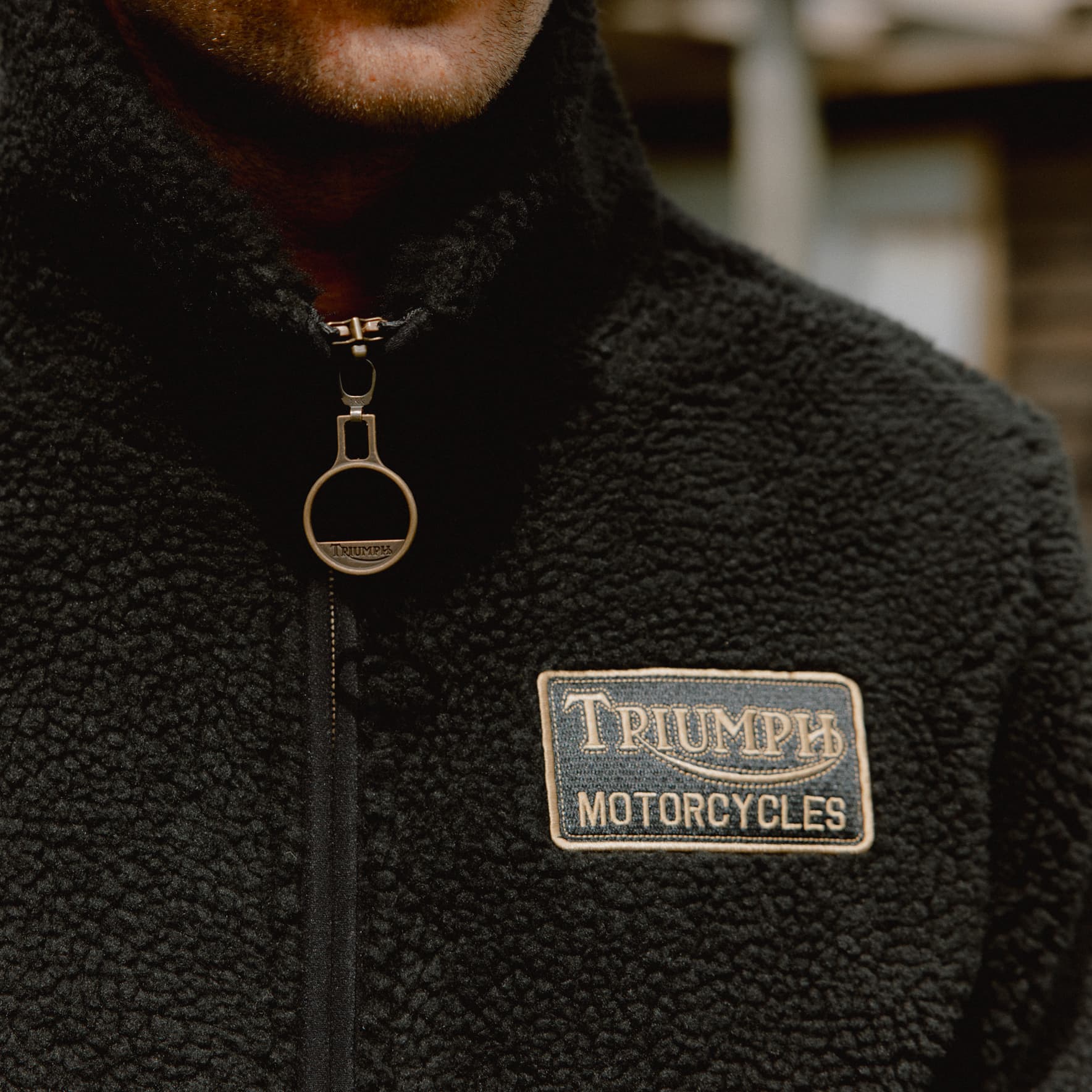 Close up of man wearing a Roadhouse High-Pile Fleece with Triumph Motorcycles badge in gold