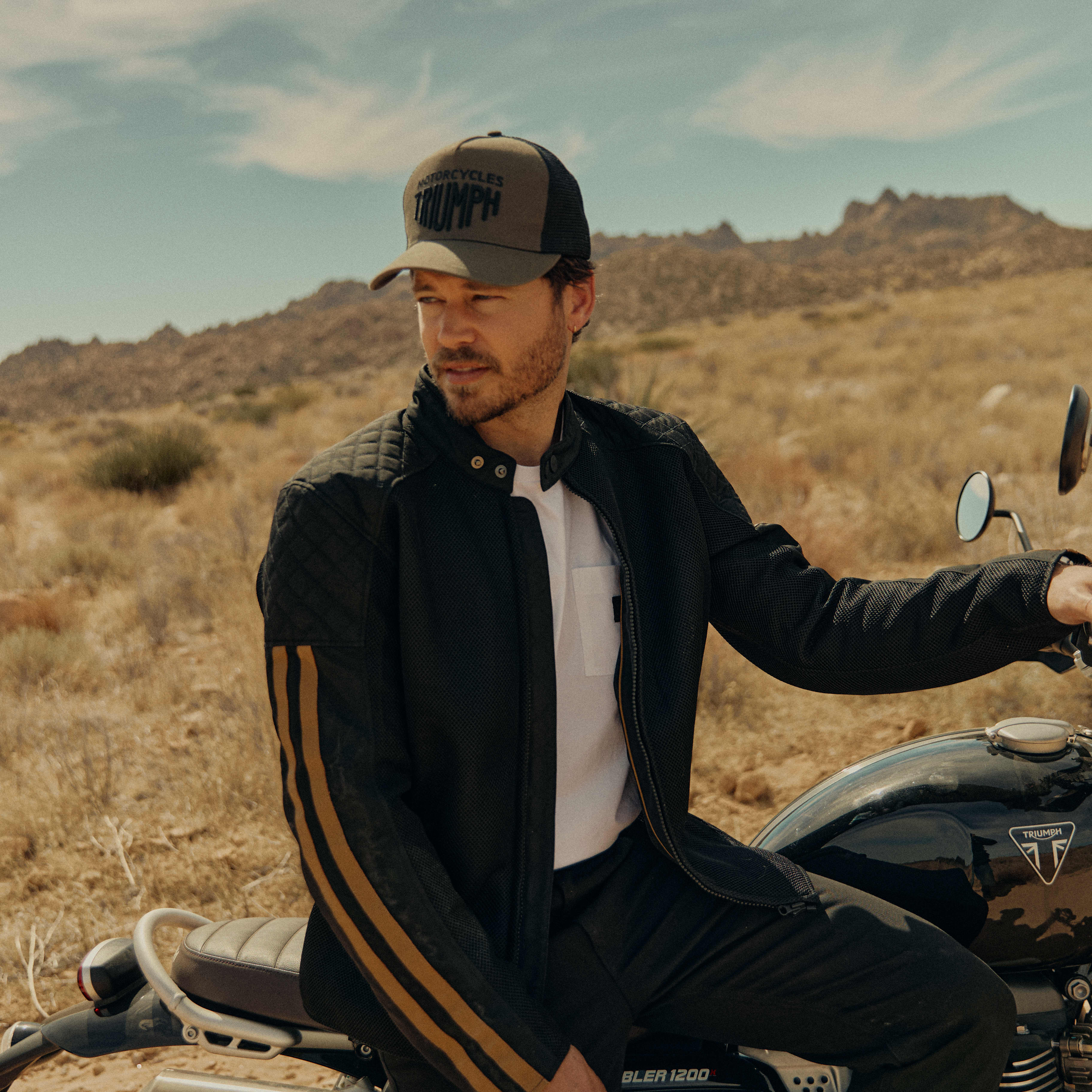 Mans back on a Triumph Motorcycle while wearing a yellow Triumph Braddan Jacket