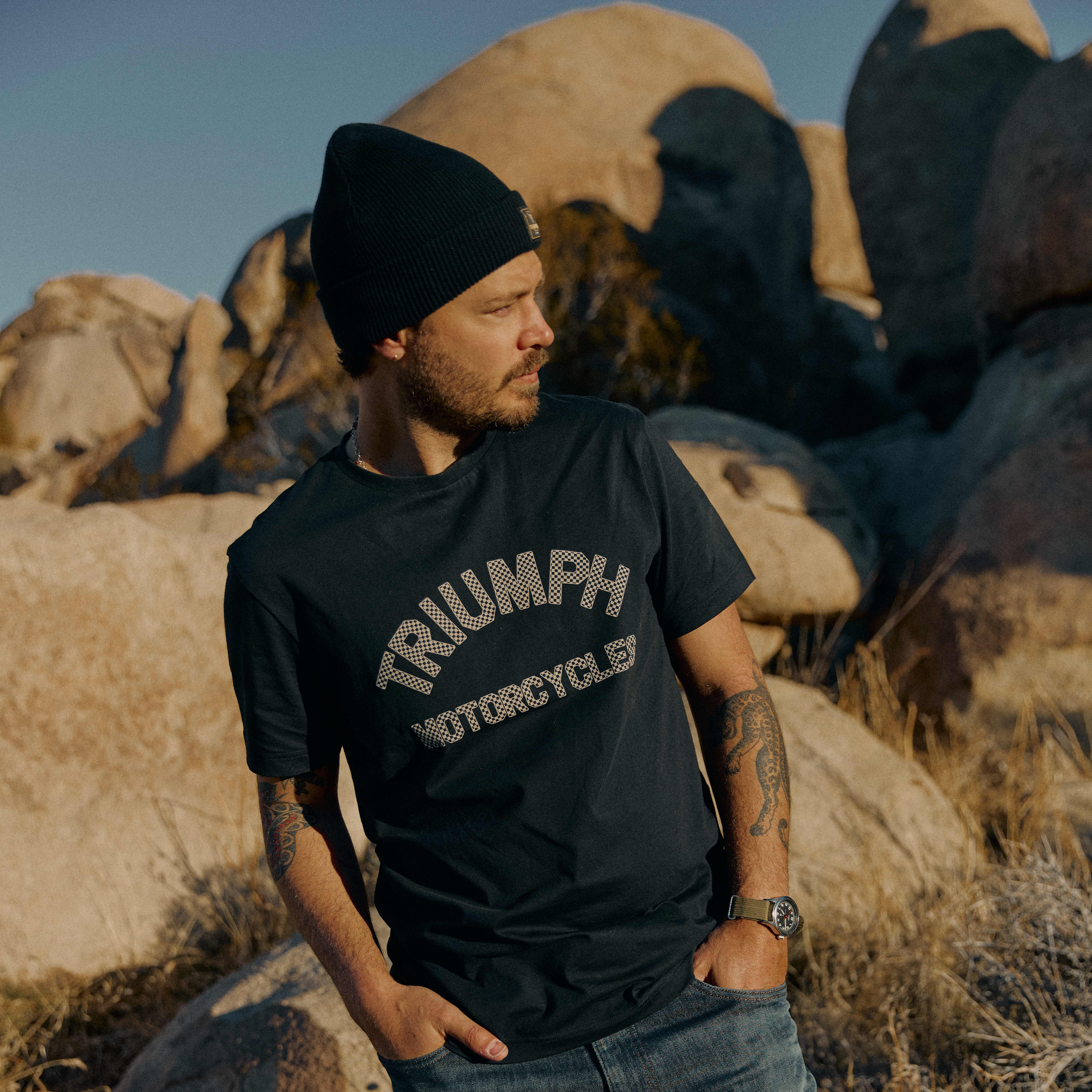 Man in the desert wearing a black checkerboard Triumph Motorcycles T-Shirt