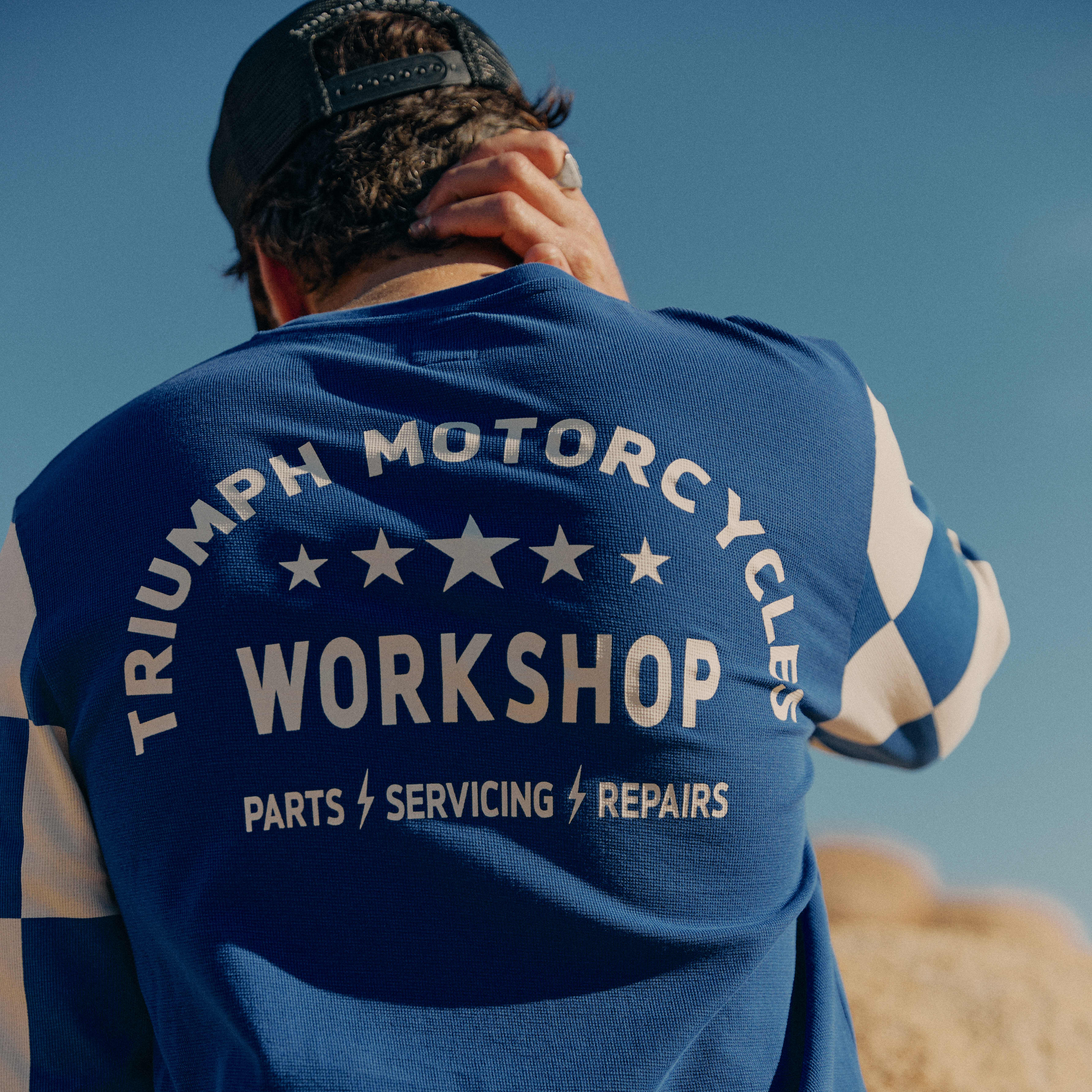 Close up of a man's long sleeve blue tee with Triumph Motorcycles Workshop graphic