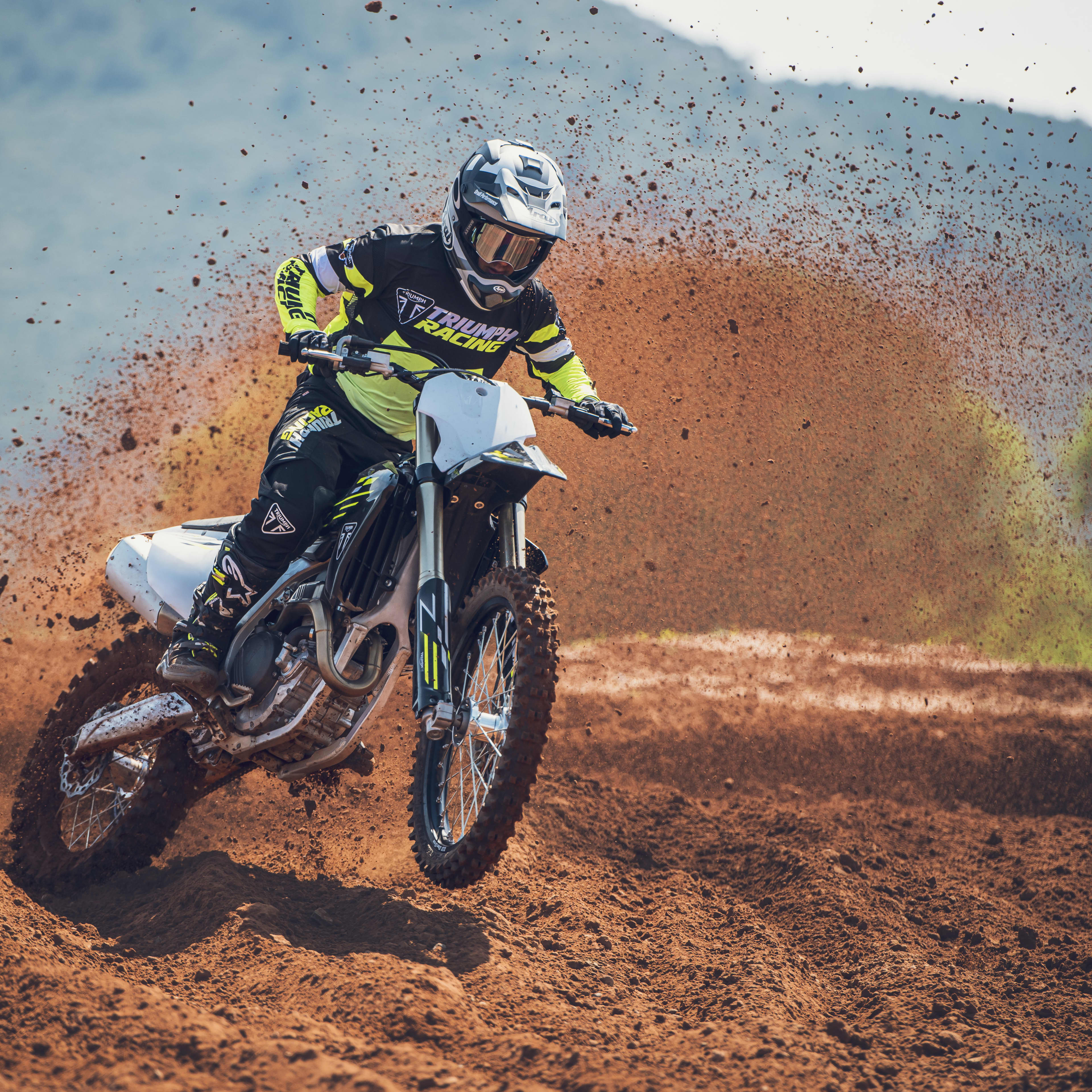 Mans back on a Triumph Motorcycle while wearing a yellow Triumph Braddan Jacket