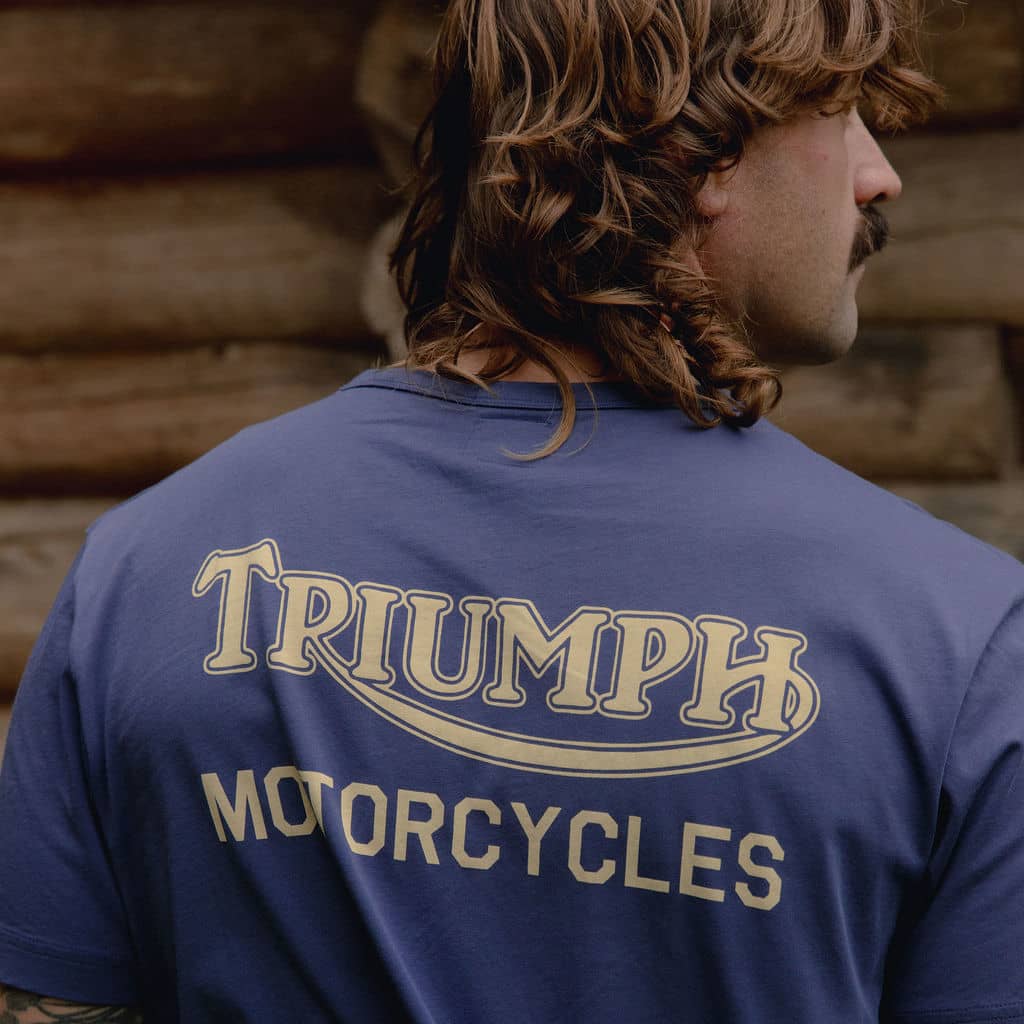 Man outside a cabin with a blue Triumph Heritage t-shirt