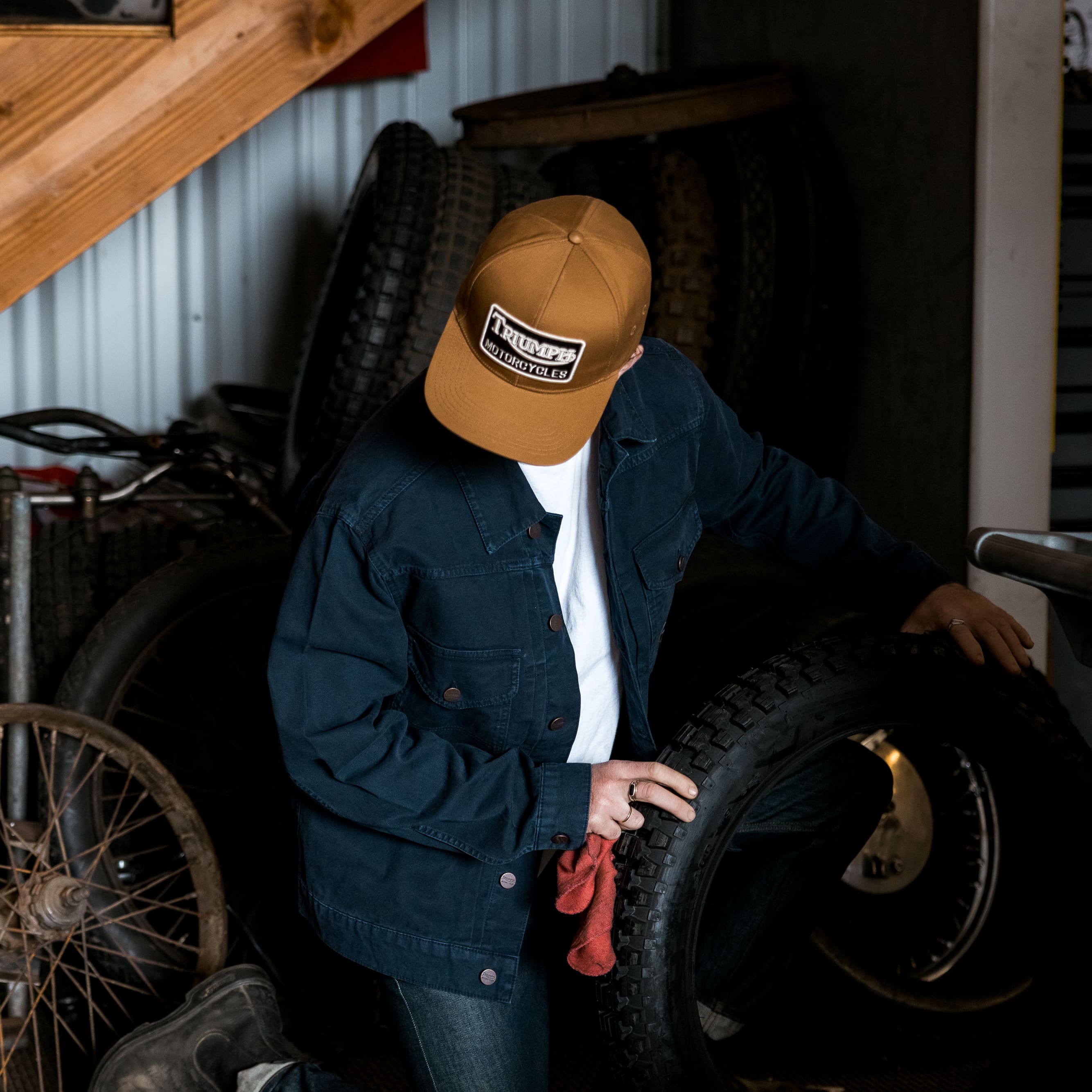 Man kneeling down wearing a Triumph Heritage Cap