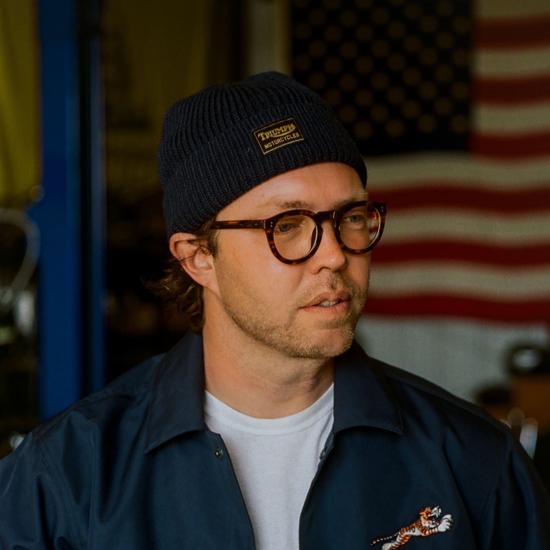 Man stood in workshop wearing a Triumph Heritage Jacket and Hat
