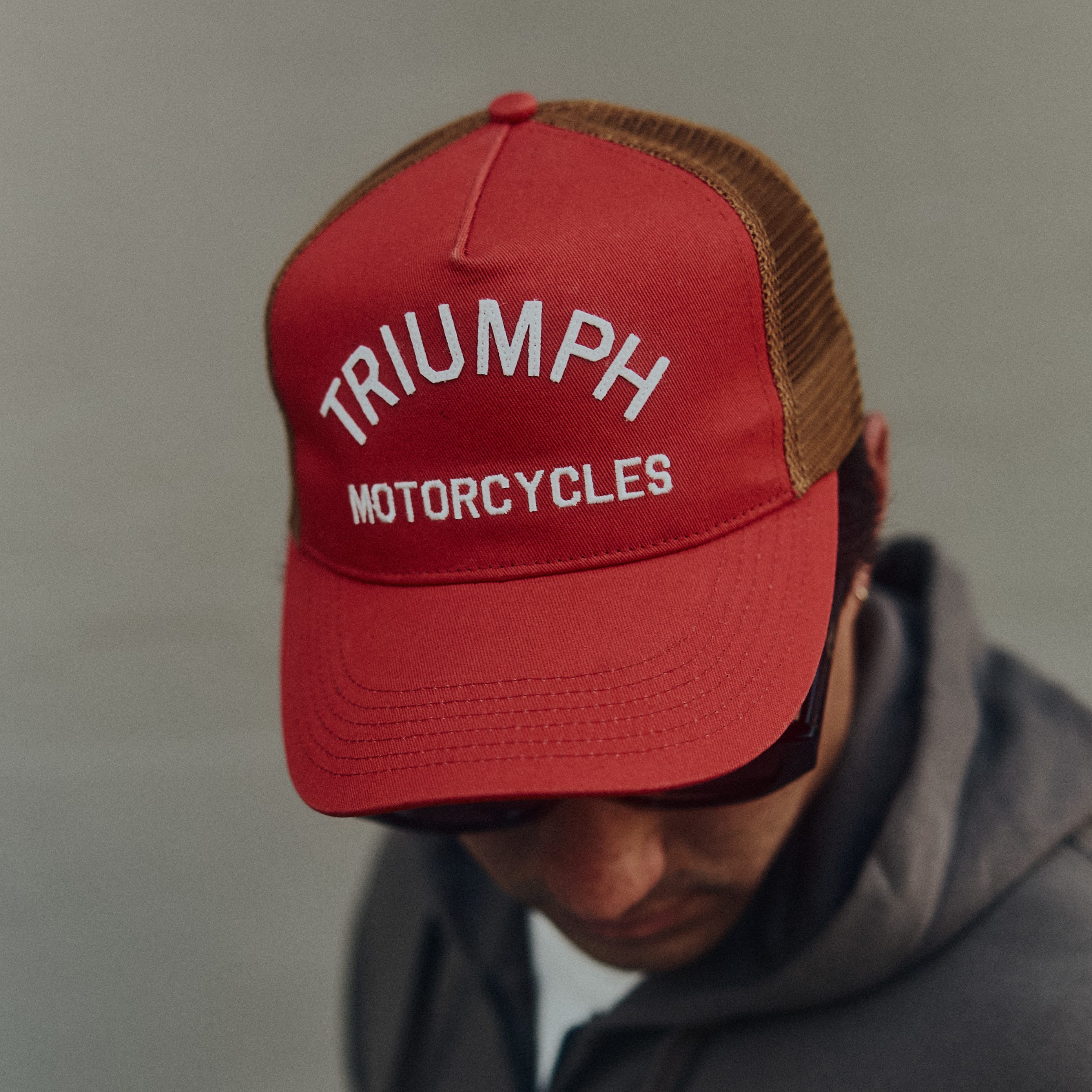 Man in jacket wearing red Triumph Motorcycles Cap