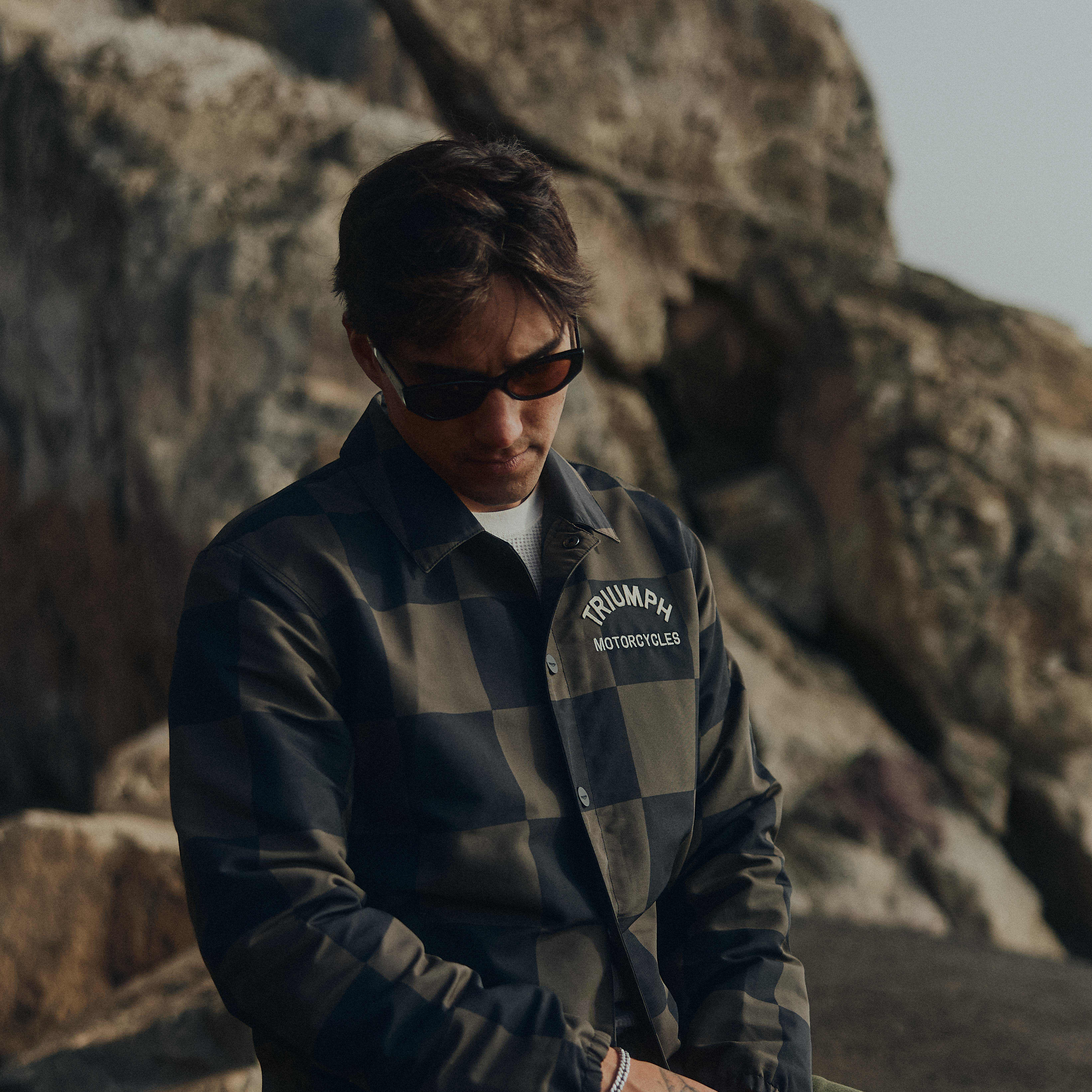 Man sat down wearing the checkerboard coach jacket