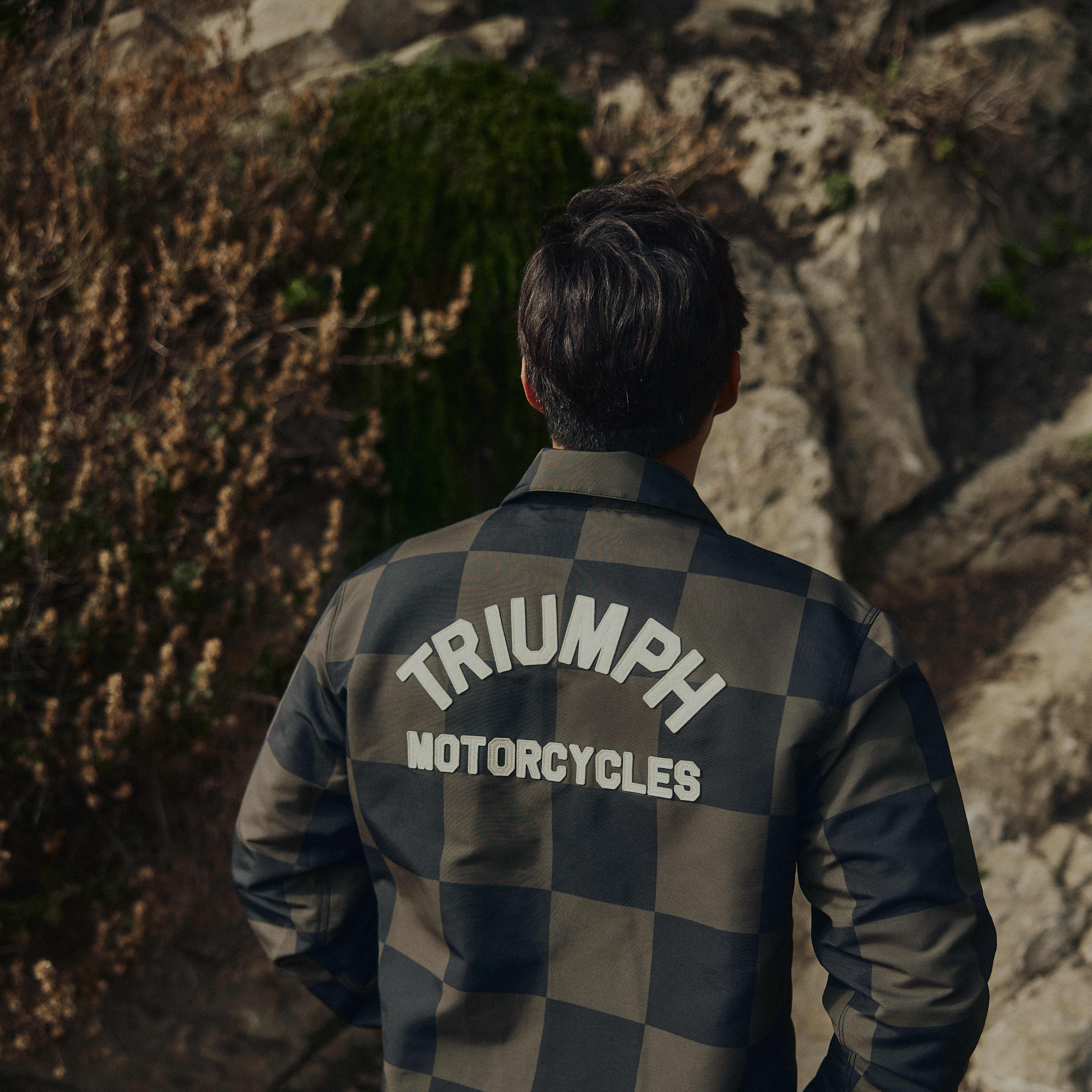 Man wearing a checkerboard Triumph Motorcycles jacket