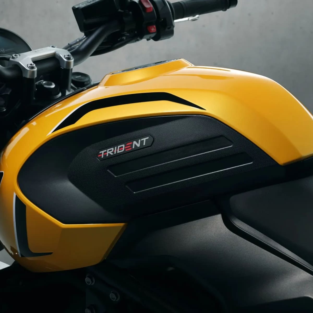 Close-up of a bright yellow and black fuel tank on a Triumph Trident motorcycle.